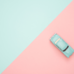 Türkisfarbenes Spielzeugauto im Retrostil auf einem zweifarbigen Hintergrund in Mint und Rosa